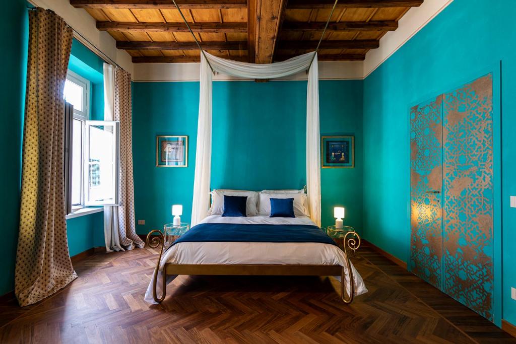 a bedroom with blue walls and a bed with a canopy at Palazzo Fauzone Relais in Mondovì