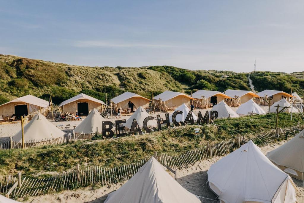 a bunch of tents on a beach with hills at Beachcamp Bloemendaal Surf Resort in Overveen