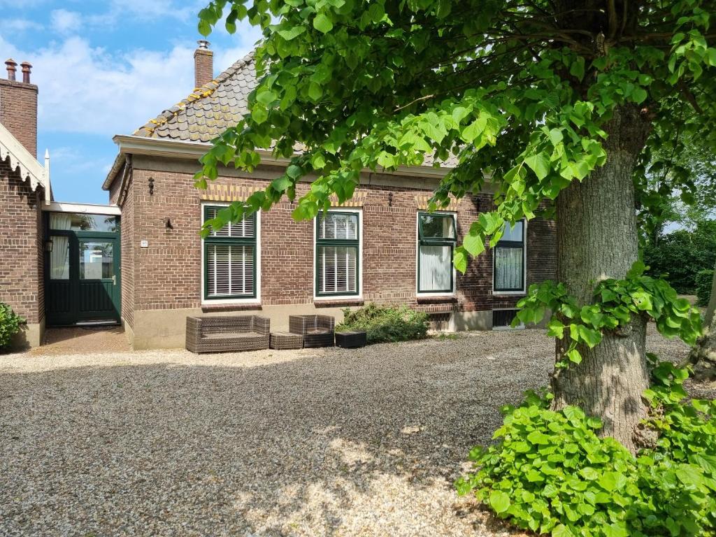 une maison en briques avec un arbre devant elle dans l'établissement Het Voorhuis boerderij Hoeve Vrede Best, à Weesp