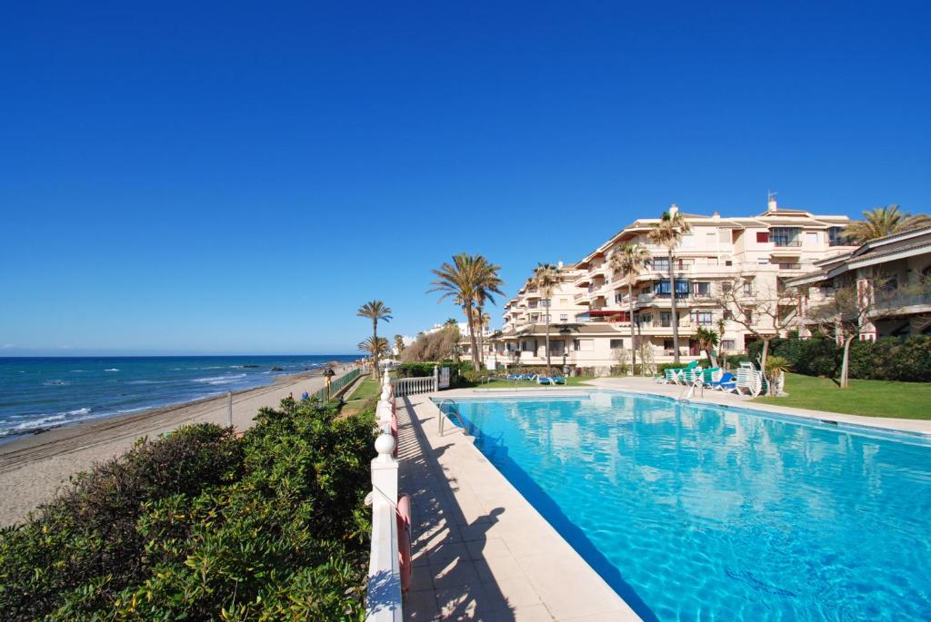 a swimming pool next to a beach with condos at Casa Linda La Lubina, front the beach La Lucera, Riviera del Sol in Sitio de Calahonda