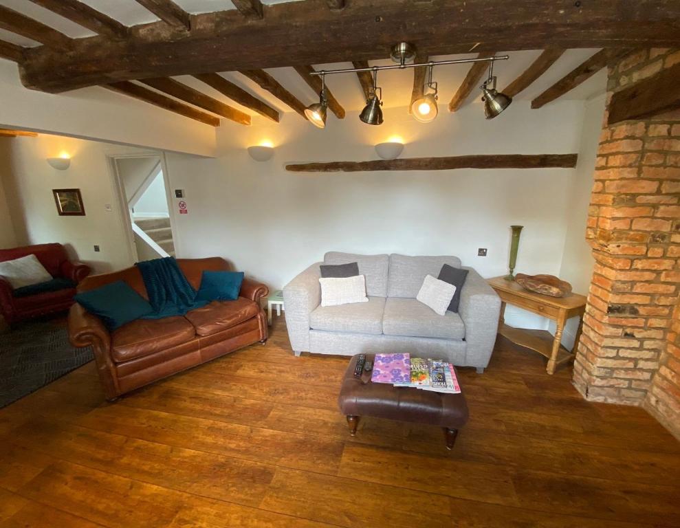 a living room with a couch and a chair at Stoop Cottage - in the heart of Quorn in Quorndon