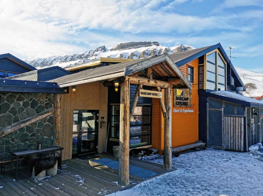 a building with a snow covered mountain in the background at Basecamp Hotel in Longyearbyen