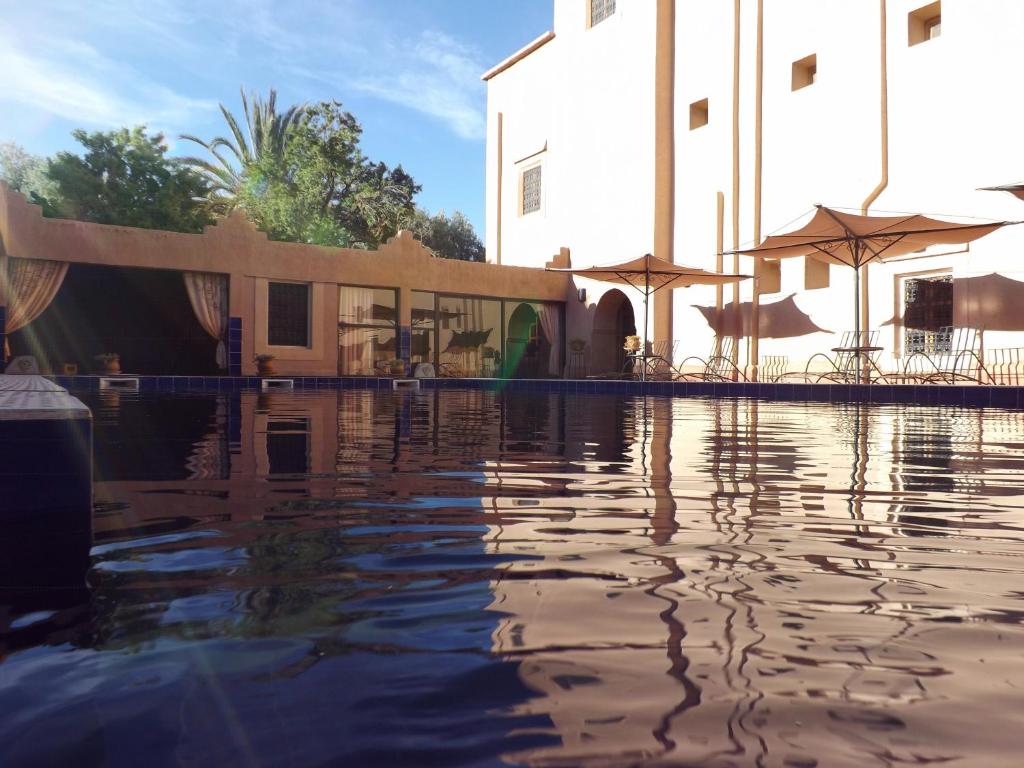 une piscine d'eau en face d'un bâtiment dans l'établissement Kasbah Ait ben Damiette, à Skoura