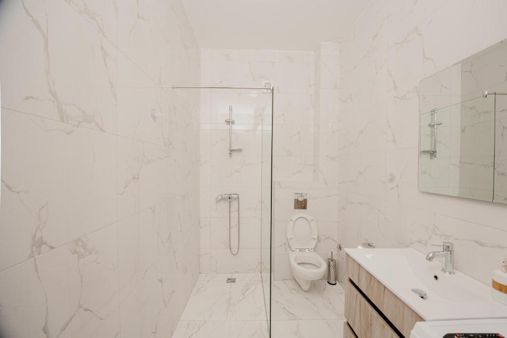a white bathroom with a shower and a toilet at Trsteno Beach Apartments in Budva
