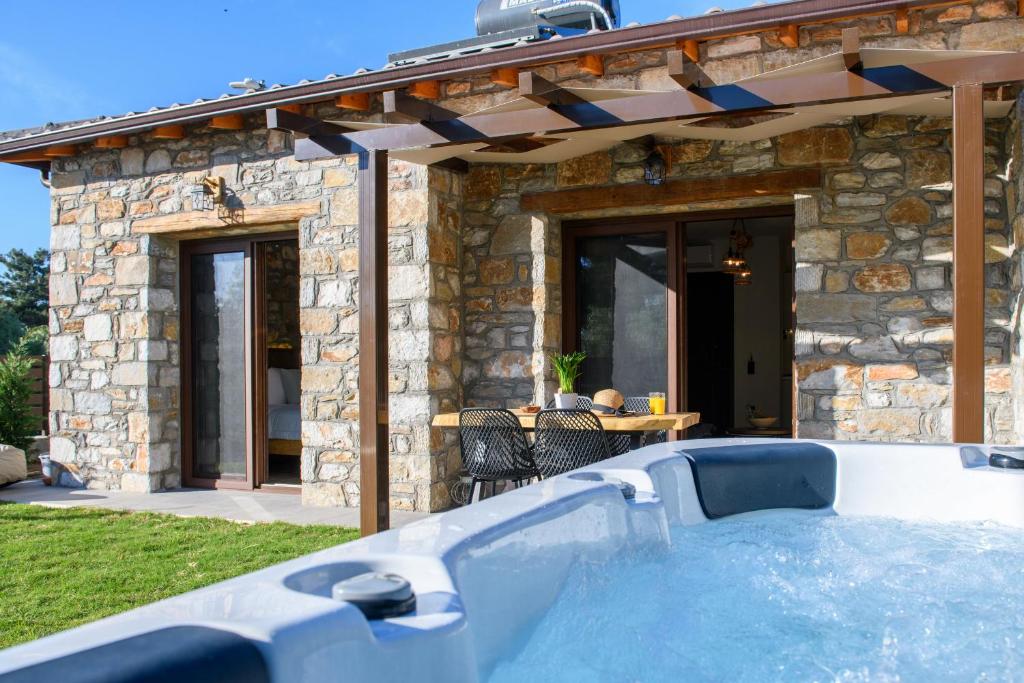 a hot tub in front of a stone house at La Terra Petra in Skala Rachoniou