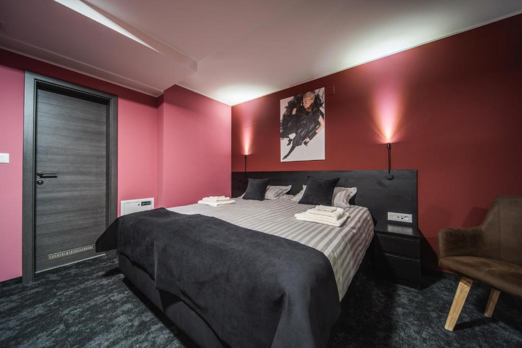 a bedroom with a large bed with red walls at Rustica Rooms in Čakovec
