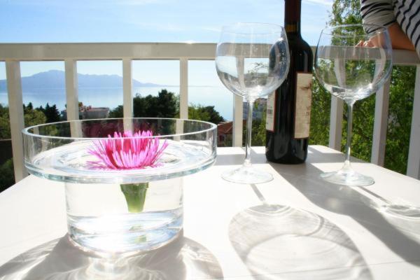 zwei Weingläser und eine Blume in einer Schüssel auf einem Tisch in der Unterkunft Apartments Slavena in Gradac