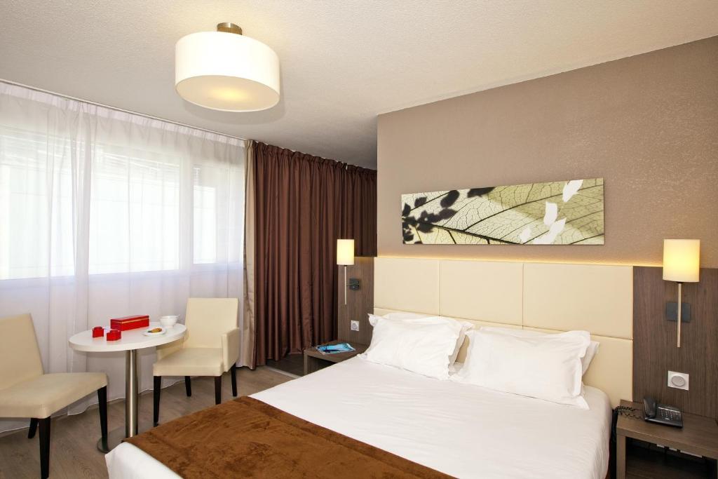 a hotel room with a bed and a table and a room at Séjours & Affaires Montreuil Saint Mandé in Montreuil