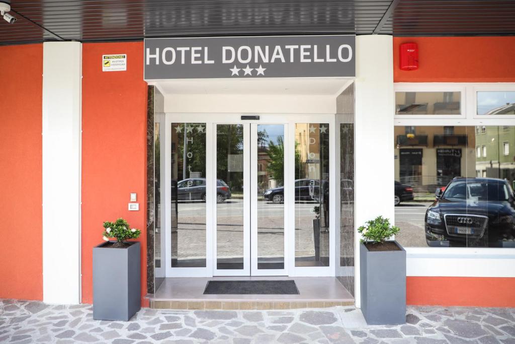 a hotel front door with two potted plants in front at Hotel Donatello in Modena
