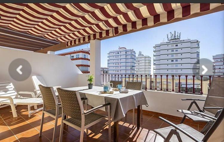 d'une table et de chaises sur un balcon avec vue sur les bâtiments dans l'établissement Ático con vistas cerca del mar - Penthouse - parking - terraza, à Torre del Mar