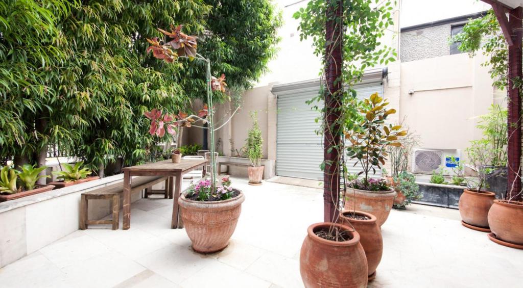 a patio with a bunch of potted plants and a table at Excelsior Apartments at Glebe in Sydney