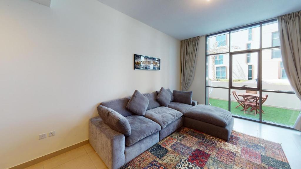 a living room with a couch and a large window at Hometown Apartments - Brand New 2BR Apartment in Dubai Wharf 2 in Dubai