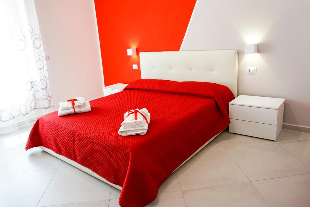 sypialnia z czerwonym łóżkiem z białymi butami w obiekcie In Centro rooms w mieście Castellabate