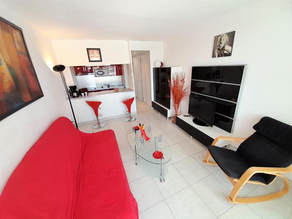 a living room with a red couch and a fireplace at Village Naturiste - Port Ambonne in Cap d'Agde