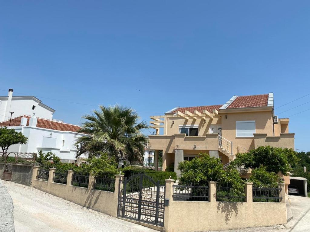 a house with a fence and a palm tree at Ceka Apartments in Ulcinj