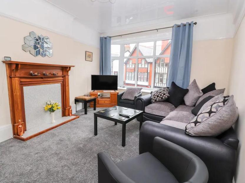 a living room with a couch and a fireplace at Seabreeze Apartment in Llandrillo-yn-Rhôs