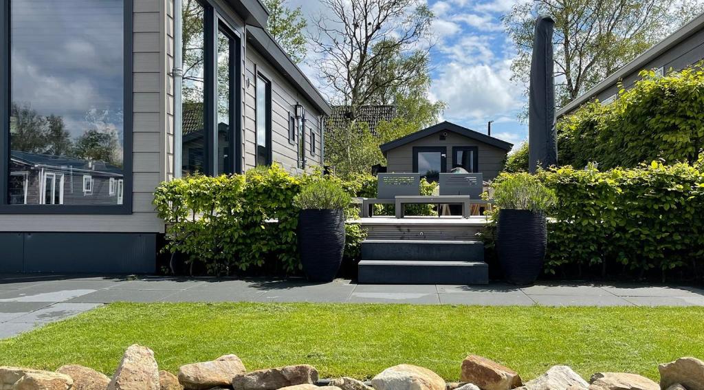 a house with a bench in a yard at PUUR Eernewoude luxe chalet direct aan open vaarwater gelegen in de Alde Feanen in Earnewâld