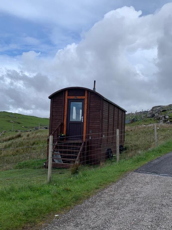 a small house sitting on the side of a road at Eco Crofters Wagon by the Beach in Oldshoremore