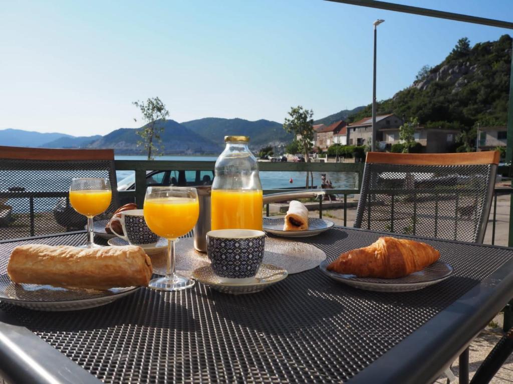 a table with bread and orange juice and drinks on it at Holiday home TONČICA - Rogotin in Rogotin