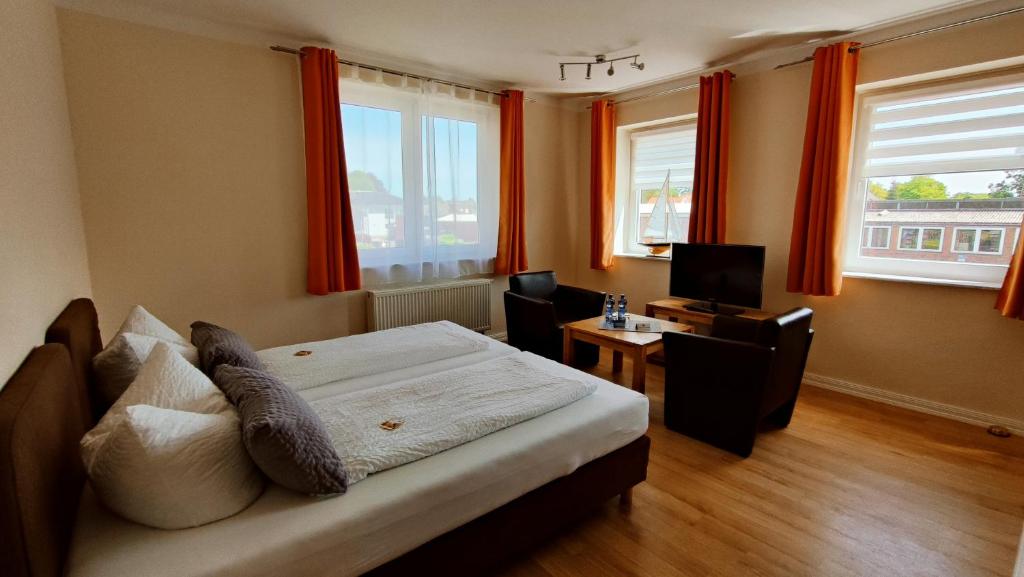 Schlafzimmer mit einem Bett, einem Schreibtisch und Fenstern in der Unterkunft Pension Glückstadt in Glückstadt