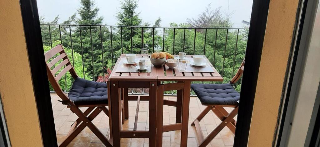 uma mesa e 2 cadeiras numa varanda com uma mesa e cadeiras em IL NIDO DELLA FENICE em Brunate