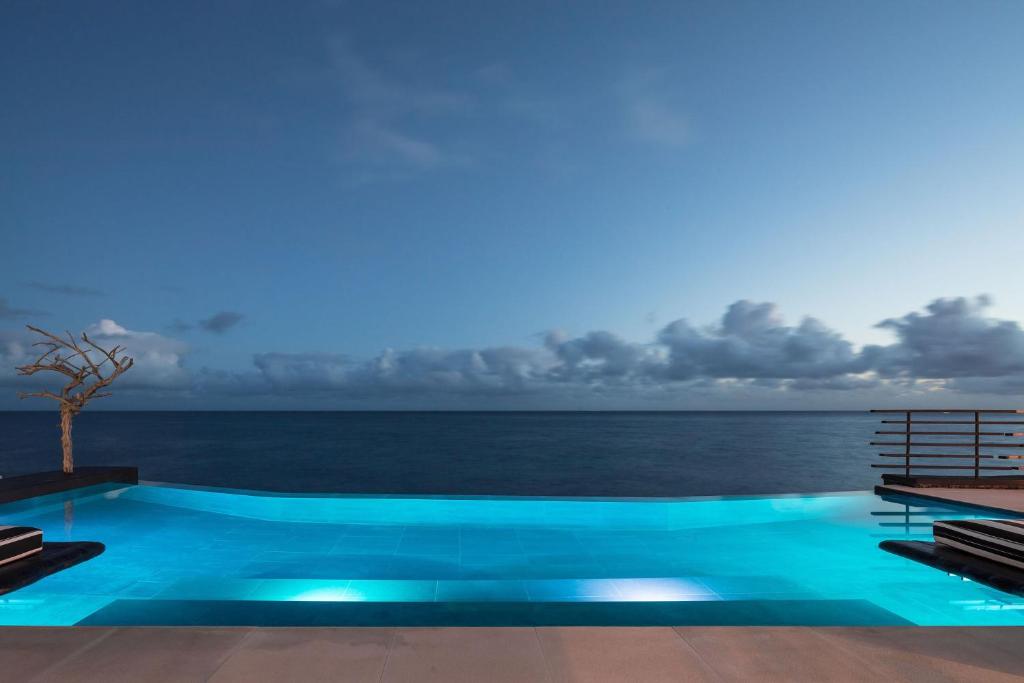 a swimming pool with the ocean in the background at White Exclusive Suites & Villas in Lagoa