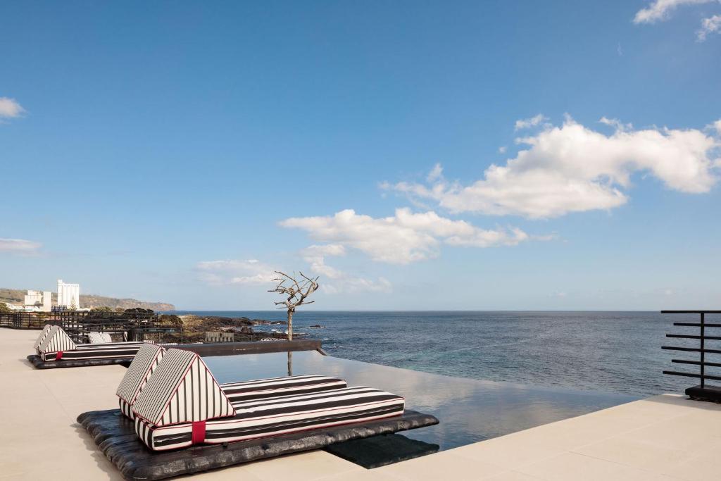 two lounge chairs sitting next to the ocean on a resort at White Exclusive Suites & Villas in Lagoa