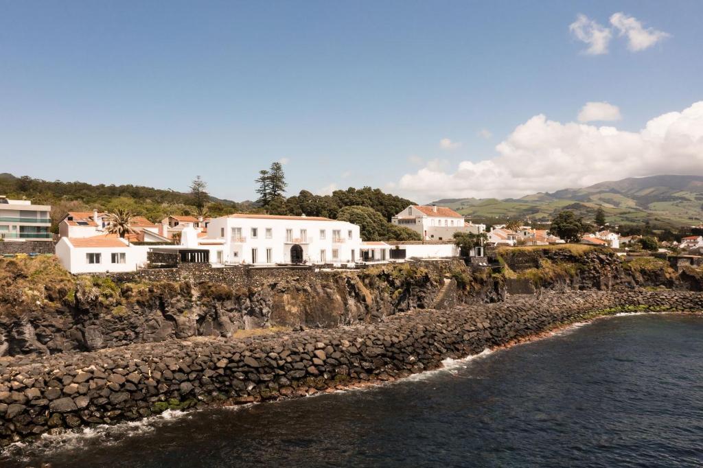 a group of white houses on a cliff next to the water at White Exclusive Suites & Villas in Lagoa
