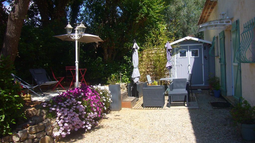 un giardino con ombrellone e alcune sedie e fiori di Les Chênes Verts a Valbonne