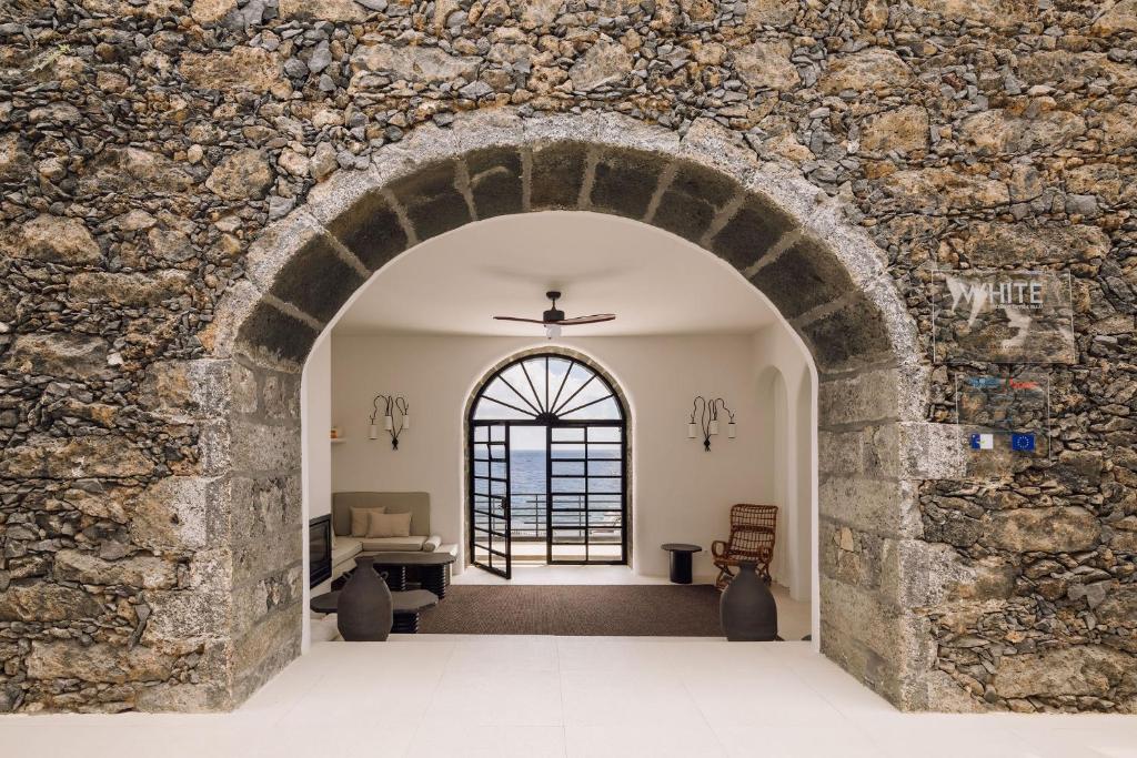 an archway leading into a room with a stone wall at White Exclusive Suites & Villas in Lagoa