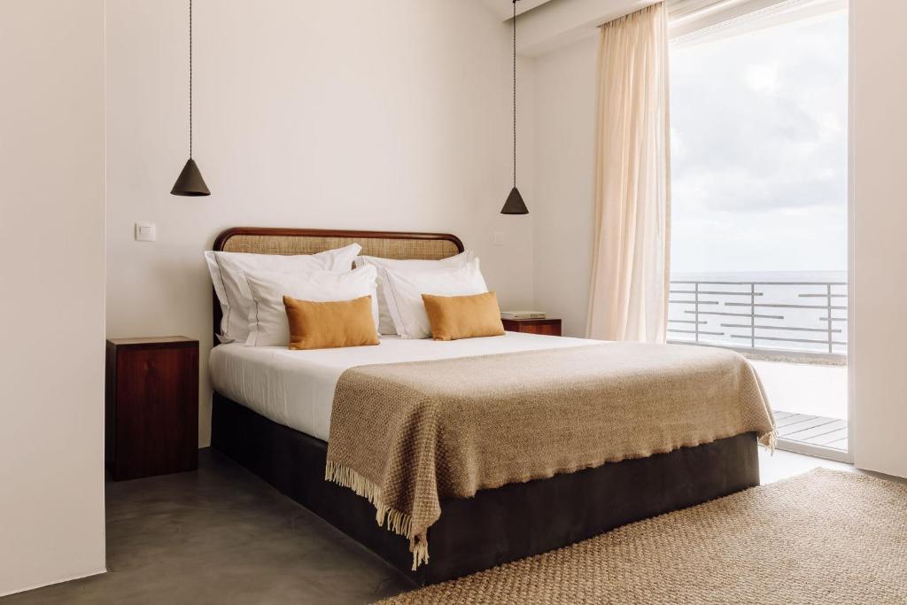 a bedroom with a large bed with a large window at White Exclusive Suites & Villas in Lagoa