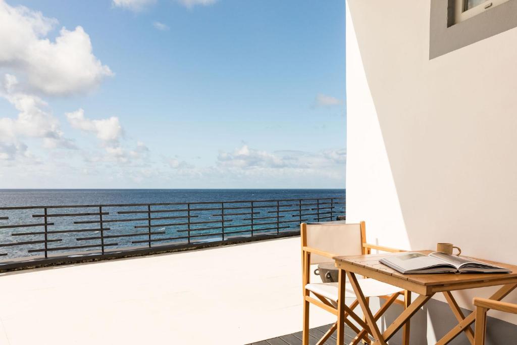a balcony with a table and a view of the ocean at White Exclusive Suites & Villas in Lagoa