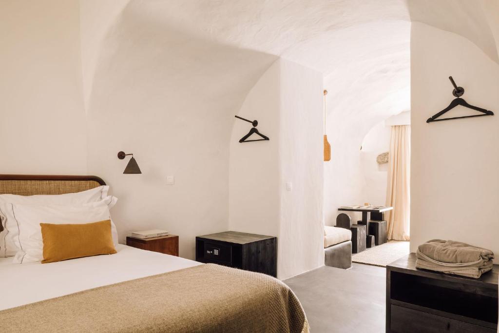 a white bedroom with a bed and a chair at White Exclusive Suites & Villas in Lagoa