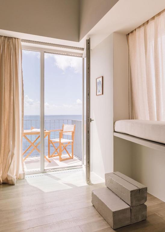 a bedroom with a bed and a balcony with the ocean at White Exclusive Suites & Villas in Lagoa