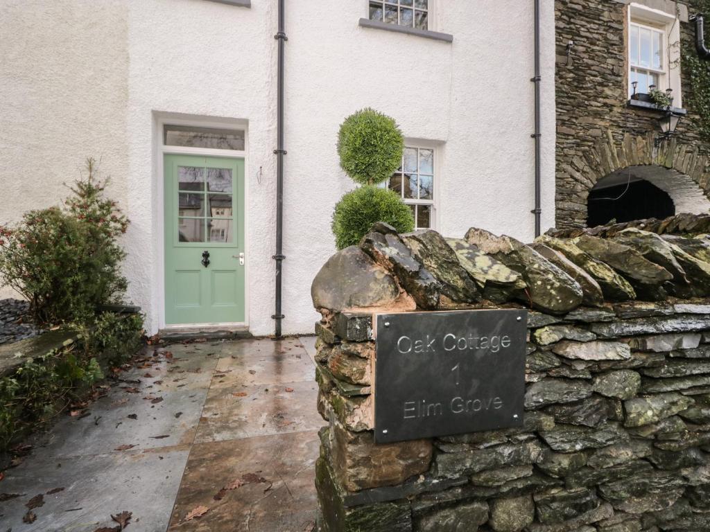 a sign on a stone wall in front of a house at Oak Cottage in Windermere