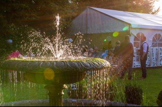 une fontaine dans un parc avec des gens debout autour de lui dans l'établissement Antrobus Hotel, à Amesbury