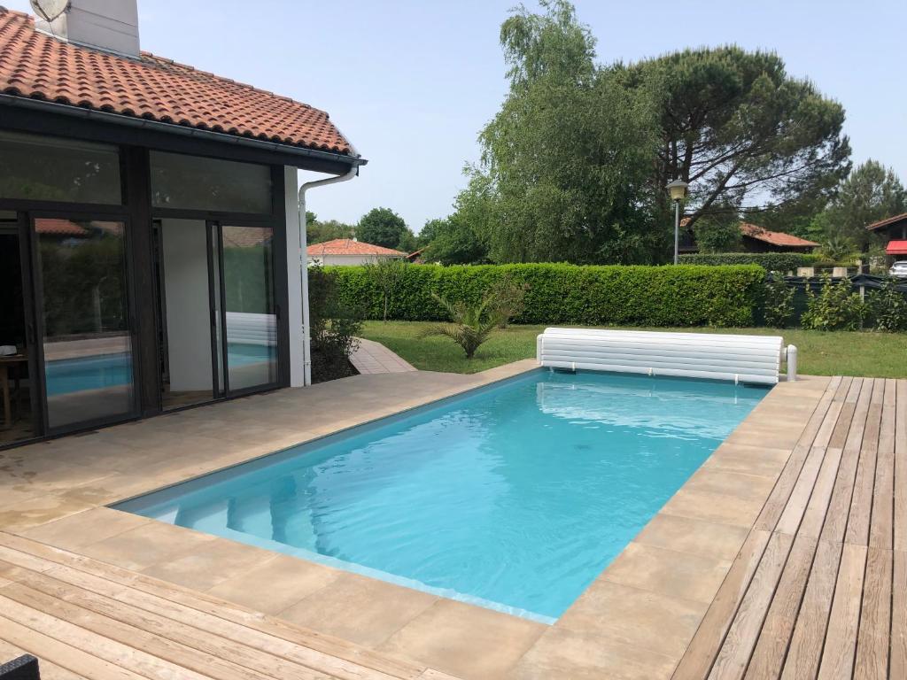 una piscina con un banco junto a una casa en Maison landaise moderne piscine chauffée spa en Lit-et-Mixe