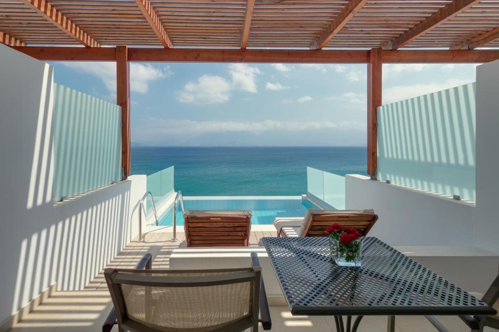 einen Balkon mit einem Tisch, Stühlen und Meerblick in der Unterkunft Miramare Resort & Spa in Agios Nikolaos