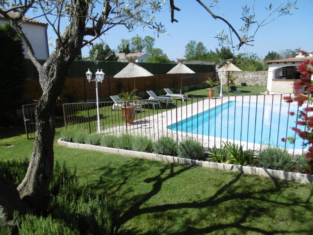 a pool with chairs and umbrellas in a yard at Les chambres d'hôtes d'Eloïse, piscine privée in Aramon