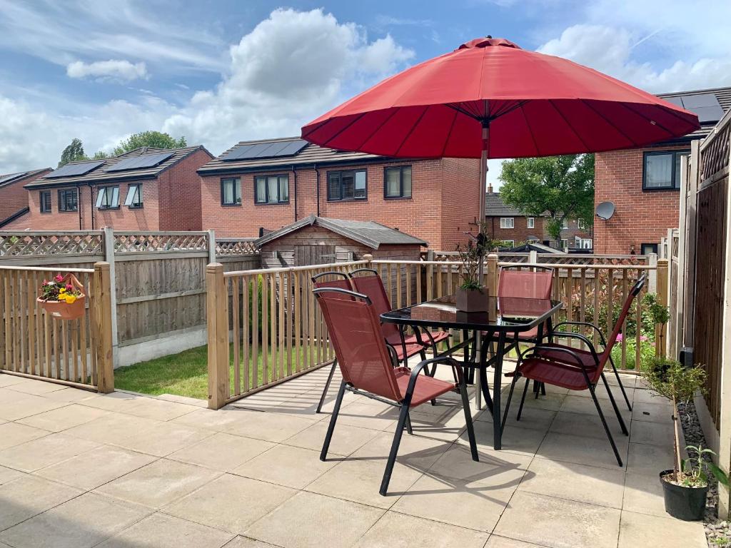 a table and chairs with a red umbrella on a patio at Maya Boutique Inn - Garden in Wythenshawe