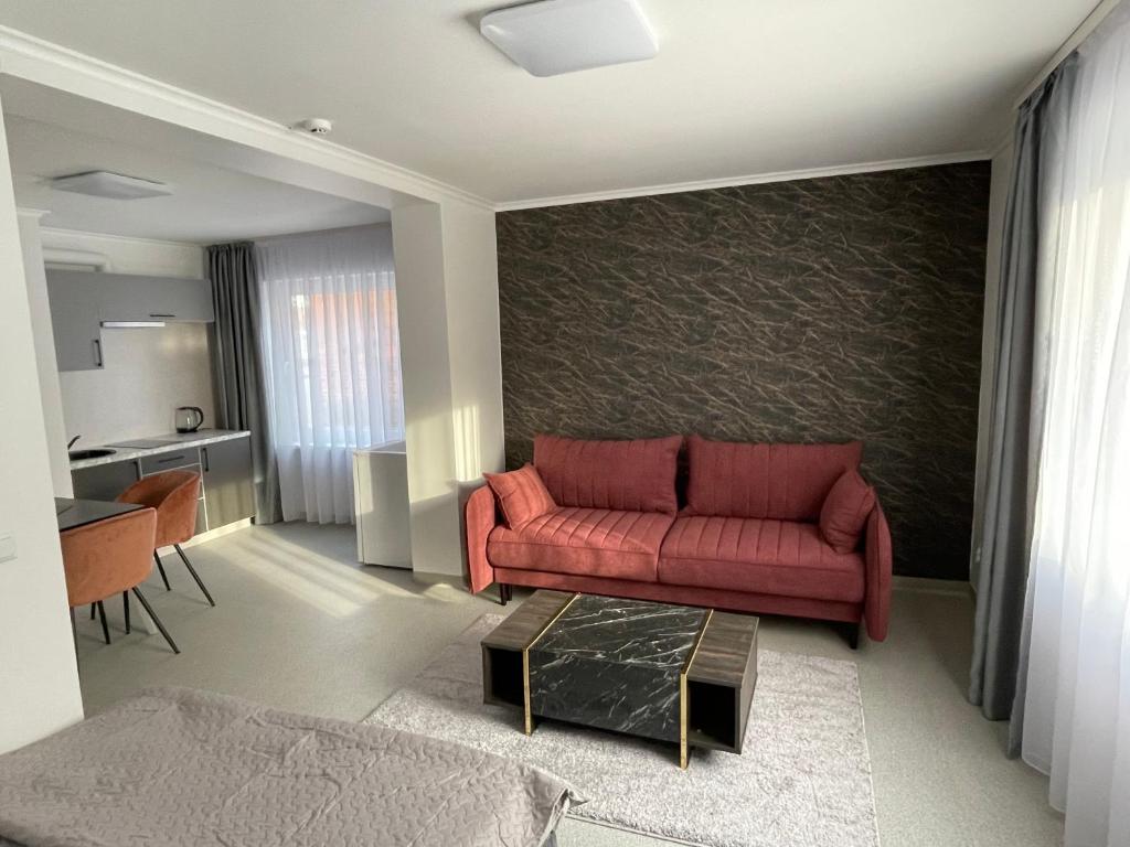 a living room with a red couch and a table at Apartamentai Rokiškio Senamiestyje in Rokiškis