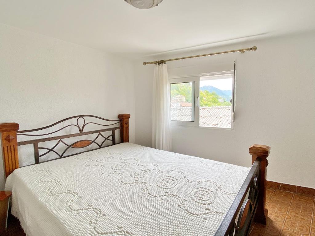 Schlafzimmer mit einem Bett und einem Fenster in der Unterkunft Apartments Pekic in Vranjina