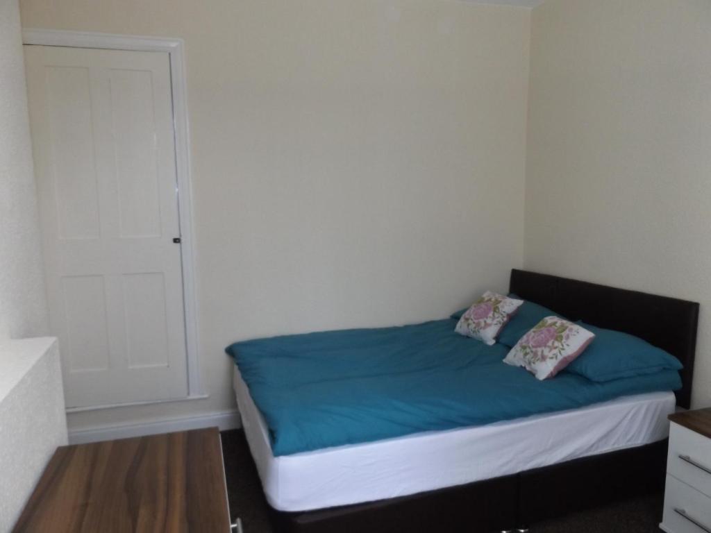 una camera da letto con un letto con lenzuola blu e una porta di MountCastle House a Leicester