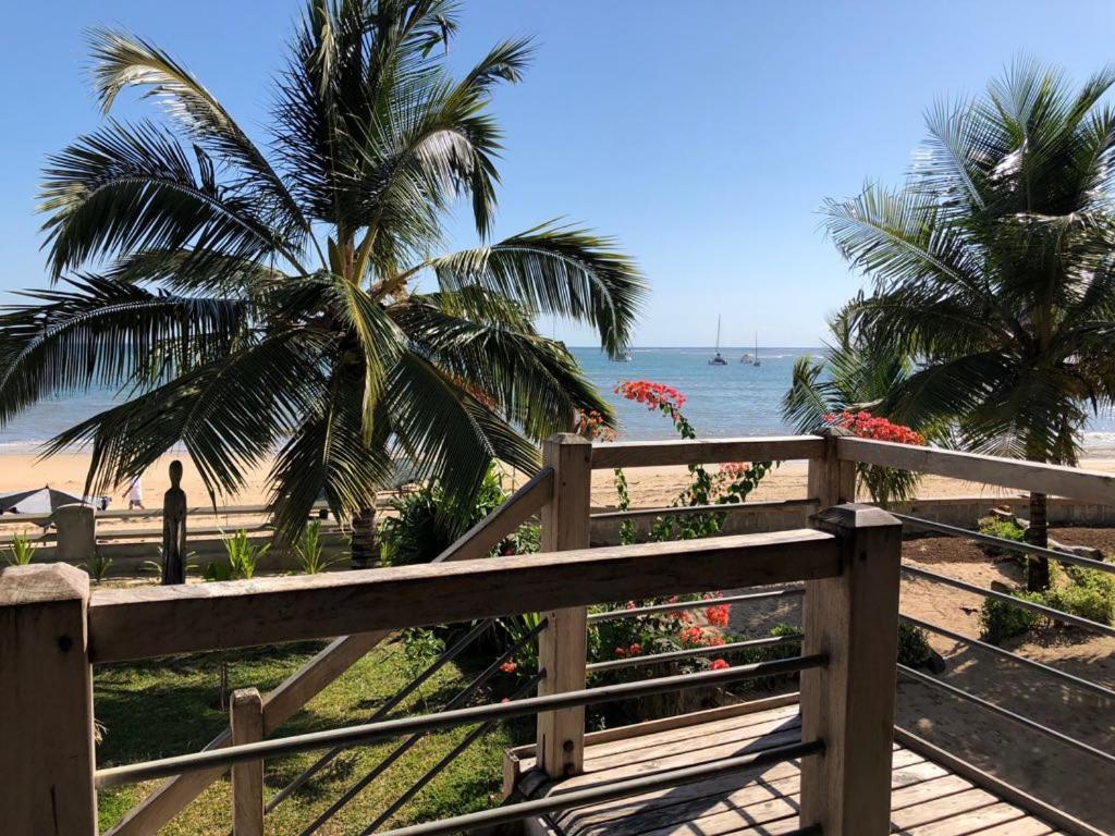 a wooden fence next to a beach with palm trees at LE TRANSAT in Ambatoloaka