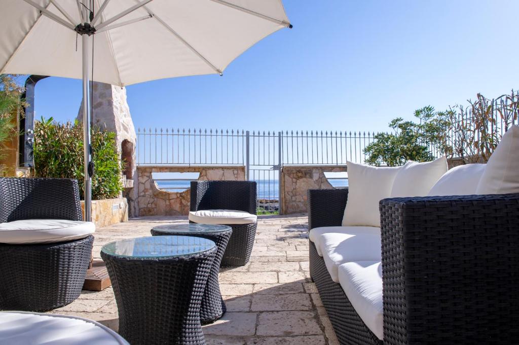 a patio with chairs and tables and an umbrella at Villa Giada on The Sea in Polignano a Mare