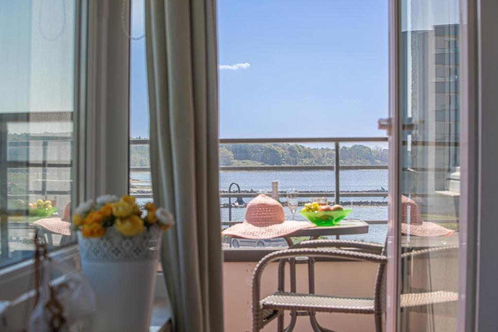 einen Balkon mit einem Tisch und Stühlen sowie Blick auf das Wasser in der Unterkunft fewo1846 - Sonne und Meer - kleines Studio-Apartment mit Balkon und Meerblick in Glücksburg