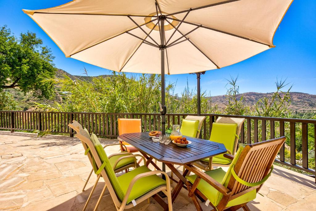 eine Terrasse mit einem Tisch und Stühlen mit einem Sonnenschirm in der Unterkunft Sermar Villa in Episkopi Pafou