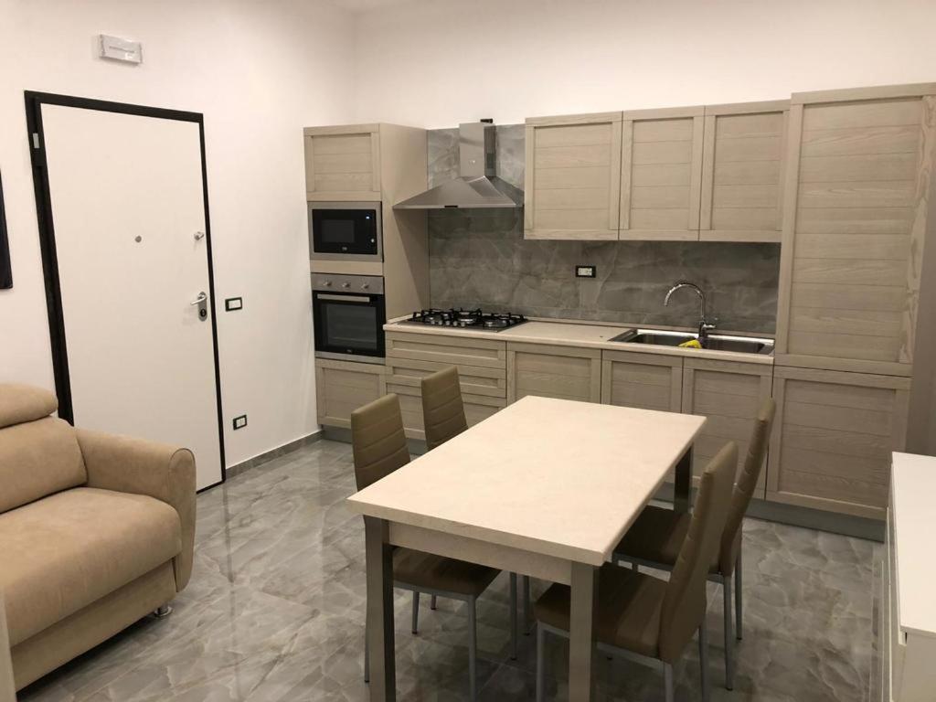 eine Küche mit einem Tisch, Stühlen und einem Sofa in der Unterkunft 13 Minuti Dal Centro in Reggio di Calabria