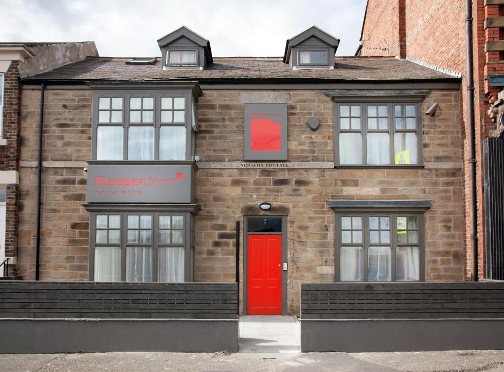 un bâtiment en briques avec une porte rouge dans l'établissement Sleeperdorm, à Newcastle upon Tyne