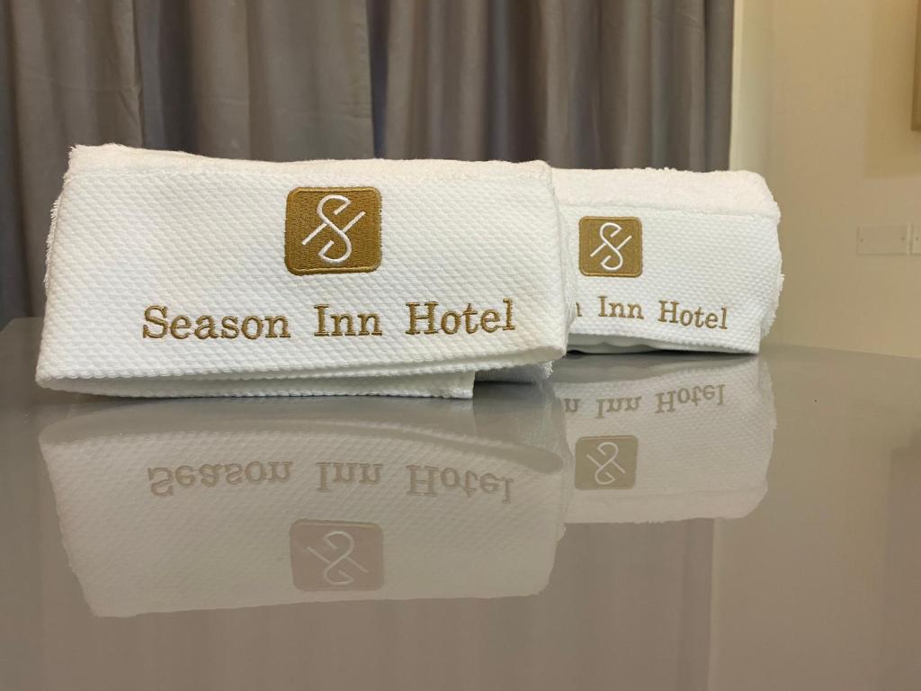Season Inn Hotel Apartment_Duqm في الدقم: تكدس المناشف وكلمة موسم نزل فندق عليهم